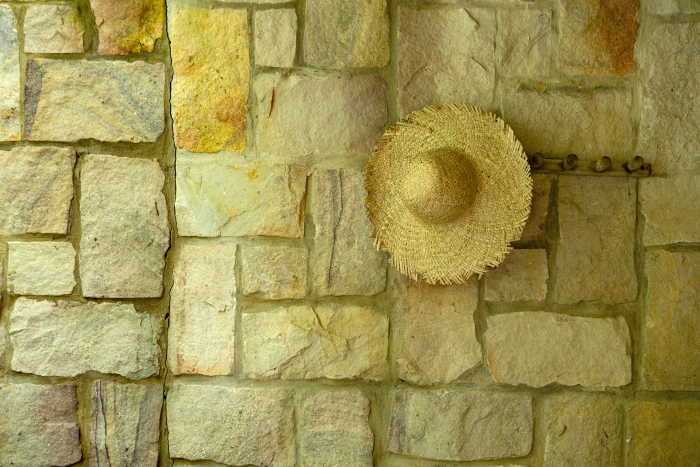 Straw hat hanging on tile wall
