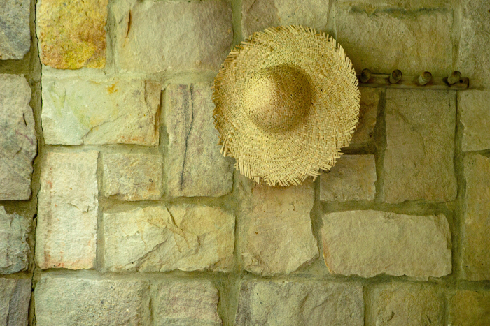 Straw hat hanging on tile wall