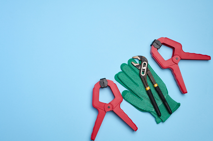 Green glove and metal universal adjustable wrench on a blue background, top view Green glove and metal universal adjustable wrench on a blue background, top view