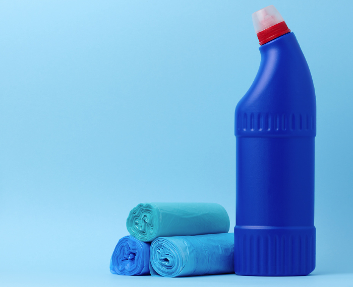 Garbage bags and a blue bottle with detergent on a blue background Garbage bags and a blue bottle with detergent on a blue background