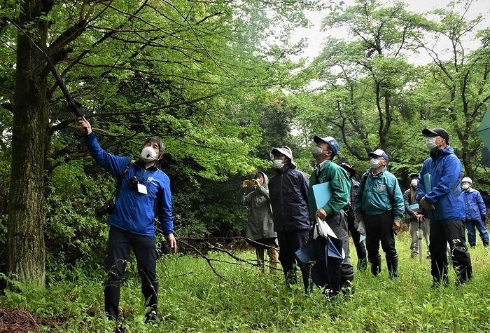 Participants looking at trees and confirming points to pay attention to. Participants check points to note while looking at trees in Naka ku, Yokohama, April 26, 2023, 2:38 p.m. Photo by Daisuke Makino.