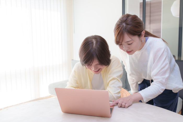 Young Japanese woman teaching a senior woman how to use a computer (People)