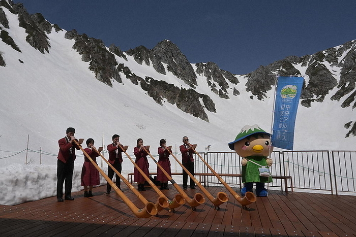 Six members of Alphorn Komakane performing with the peaks of the Central Alps in the background. The six members of Alphorn Komakane perform with the peaks of the Central Alps in the background. The peak at the back center is Mt.