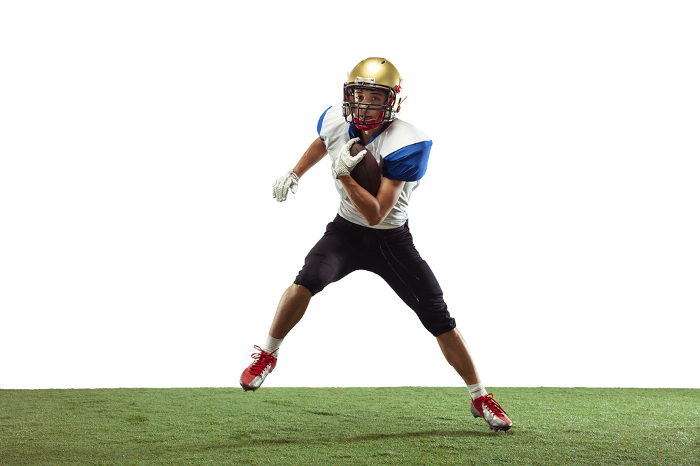 American football player in action isolated on white studio background In action. American football player isolated on white studio background with copyspace. Professional sportsman during game playing in action and motion. Concept of sport, movement, achievements.