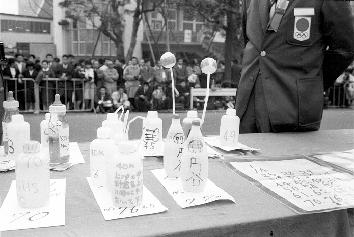 Tokyo 1964 Olympic Games Men s marathon Water station General view, OCTOBER 21, 1964   Marathon : Tokyo Olympics  Tokyo Olympics    Day 12 Marathon Kokichi Tsuburaya s  77 24, Self Defense Force Physical Education School  drink at a water station has a green ping pong ball attached to the end of the straw. The one in the center, 76, belongs to Toru Terasawa  29, Kurashiki Rayon , and the one on the far left, 70, belongs to Billy Mills  26, USA    October 21, 1964  photo date 19641021  photo location Marathon course, Tokyo