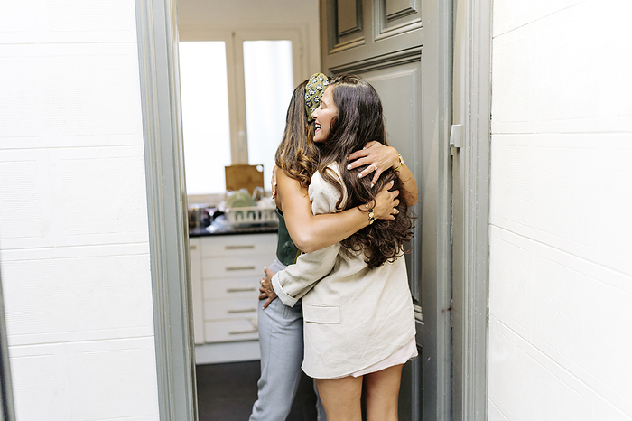 Happy woman greeting friend standing in doorway Happy woman greeting friend standing in doorway
