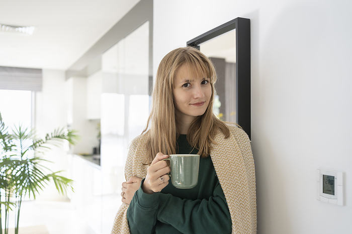 Smiling woman standing with tea cup at home