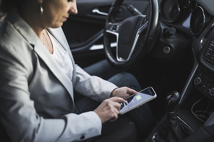Mature woman examining electric car charging app on mobile phone