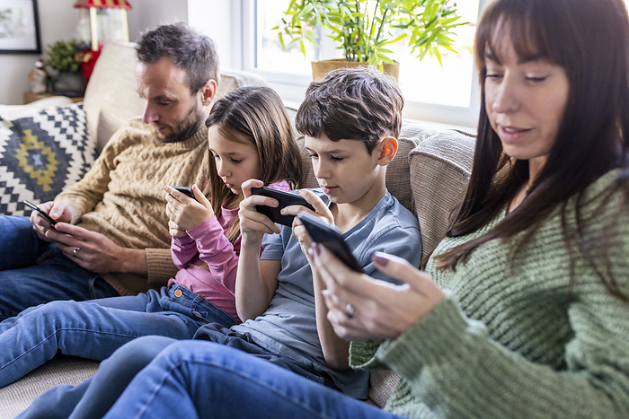 Family using mobile phone on sofa at home