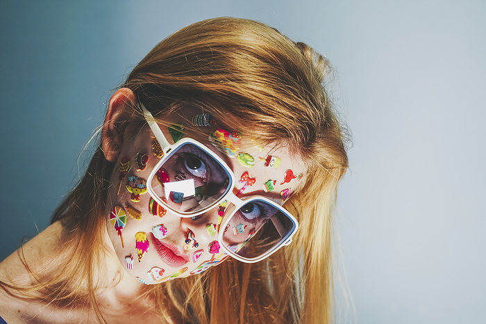 Blond woman with stickers over face wearing sunglasses