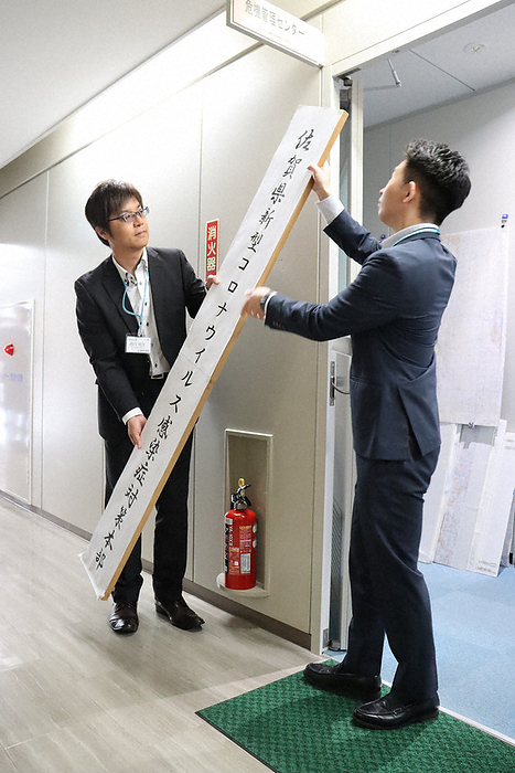 New Corona moves to Class 5. A prefectural employee removes the sign for the  Prefectural New Coronavirus Infectious Disease Control Headquarters  at the Saga Prefectural Office, which will be abolished following the transition to Category 5.