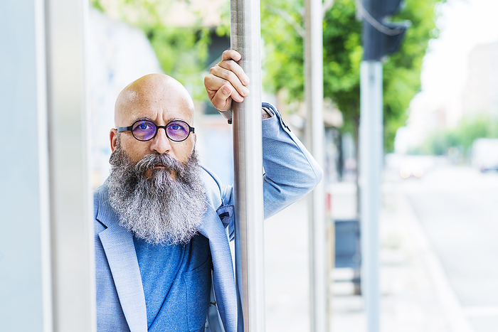 bald, bearded, bearded man standing leaning on bus stop pole