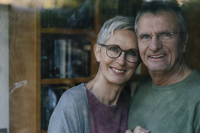 Portrait of happy senior couple behind windowpane