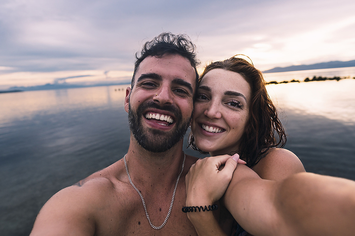 Happy couple taking selfie together at beach