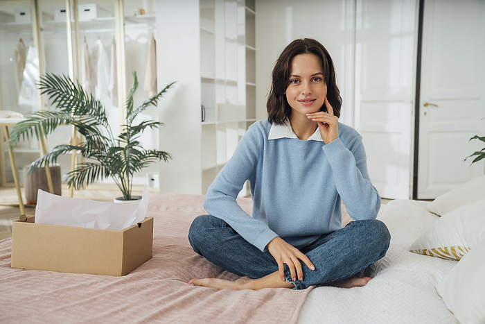 Smiling woman sitting on bed at home