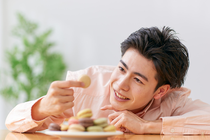 Young Japanese man staring at macarons