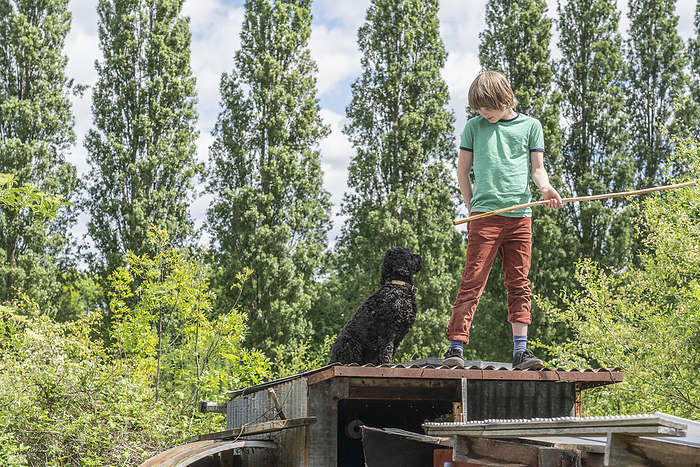 Boy with dog standing on top of allotment hut