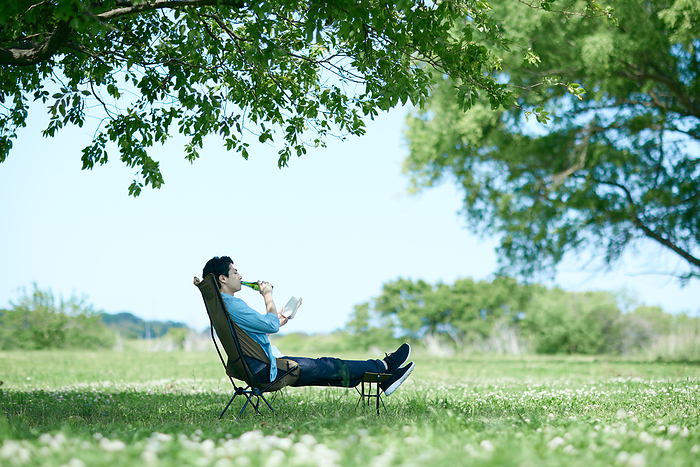 Japanese man relaxing in fresh greenery with beer