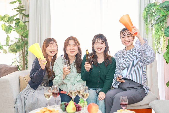Four Japanese women watching a sporting event.