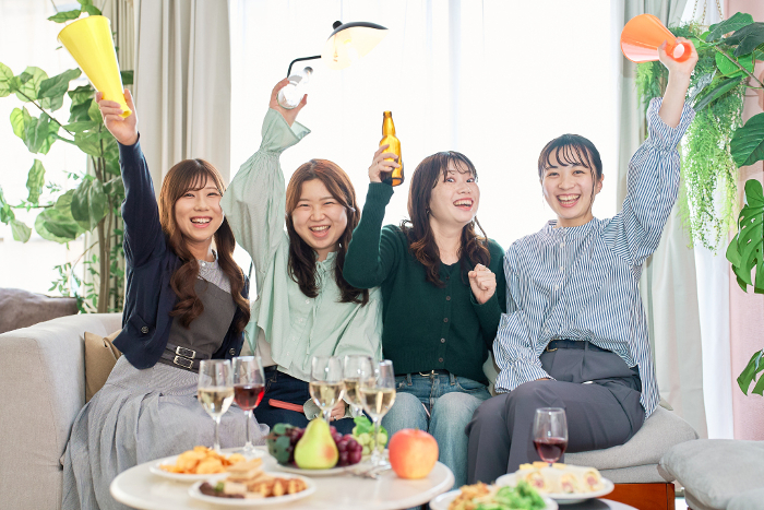 Four Japanese women watching a sporting event.