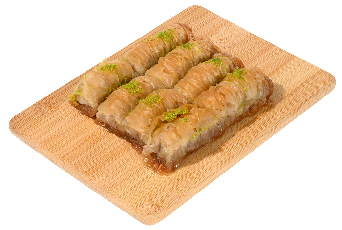 Pieces of baked baklava in honey and sprinkled with pistachios on a wooden board Pieces of baked baklava in honey and sprinkled with pistachios on a wooden board