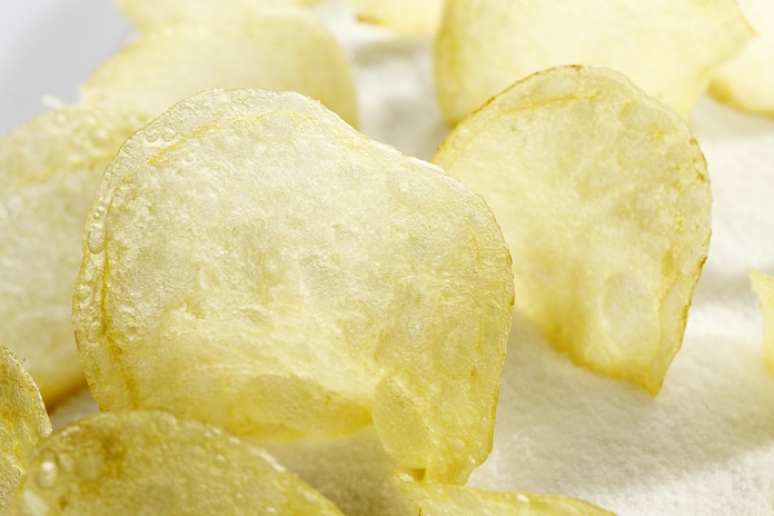 Salted potato chips on salt, close up