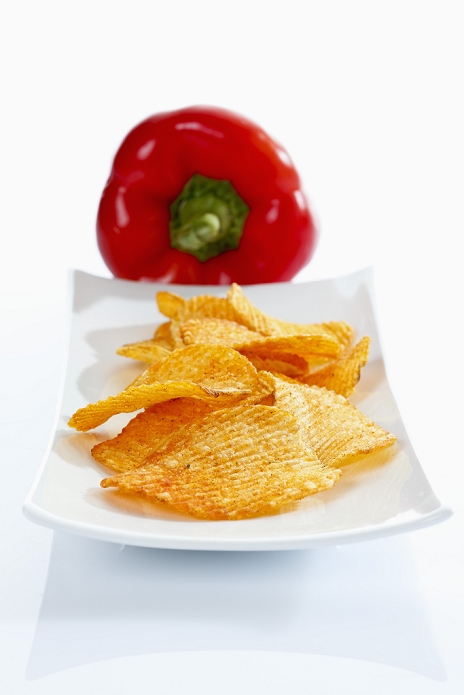 Plate of paprika potato chips on white background, close up