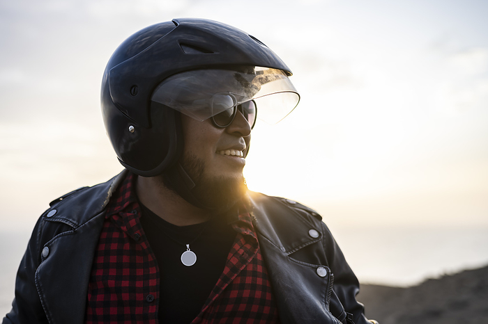 Bearded biker smiling at sunset.