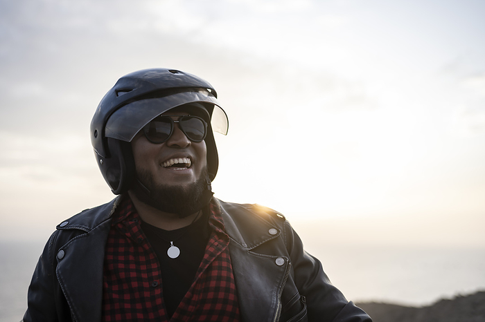 Bearded biker smiling at sunset.