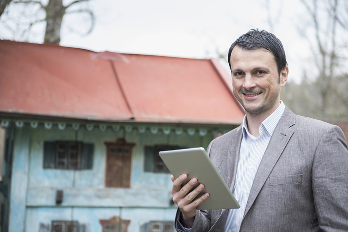 Portrait of a Man, Business, with digital PC outdoor infront of model House Portrait of a mature businessman using digital tablet outside and smiling, Bavaria, Germany