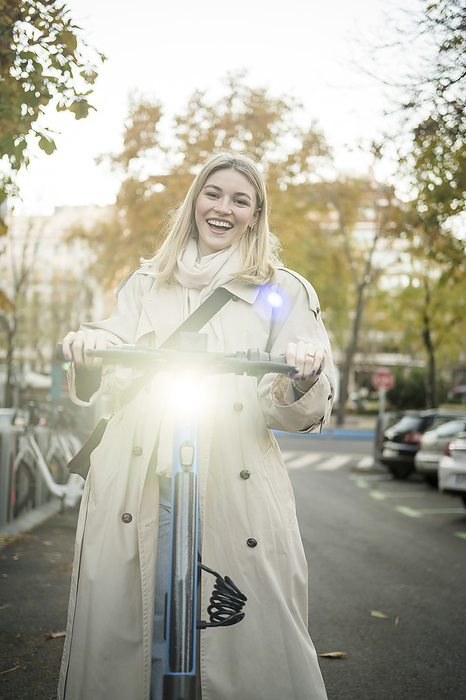 gen z girl using eco friendly transportation Madrid Spain Happy woman with illuminated electric push scooter on road