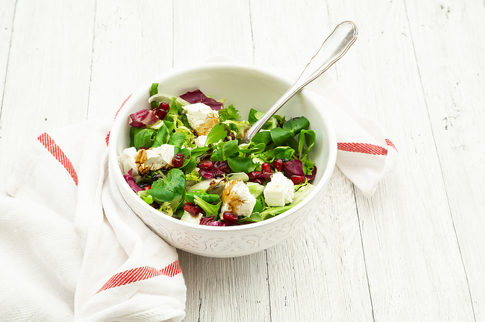 Bowl of mixed vegetarian salad with pomegranate seeds and feta cheese