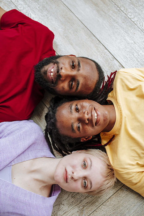 Smiling young multiracial friends lying on floor at home