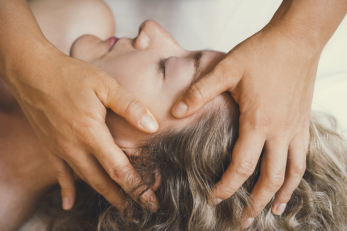 Hands of therapist giving head massage to customer in salon