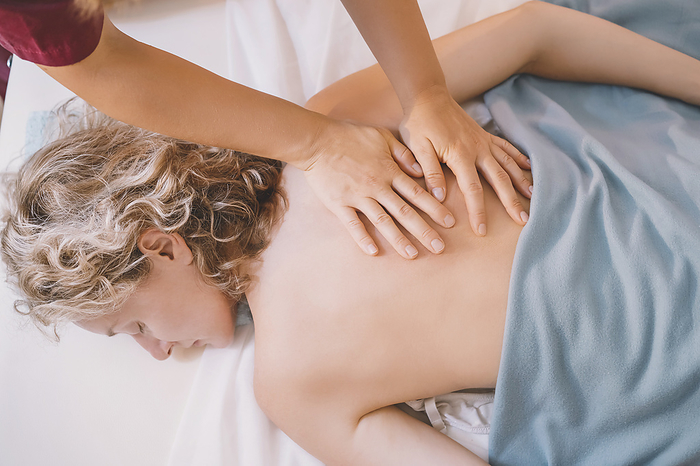 Therapist giving back massage to woman in spa