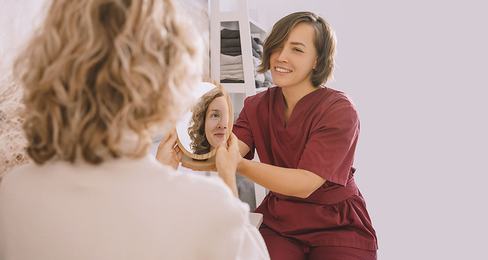 Therapist showing mirror to woman in salon