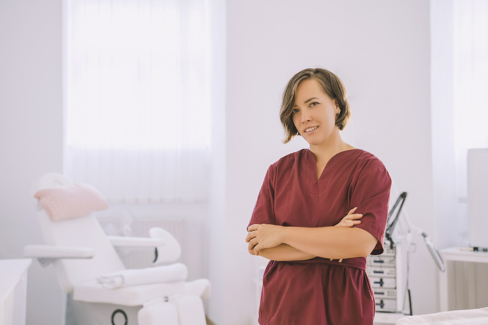 Smiling therapist standing with arms crossed in salon