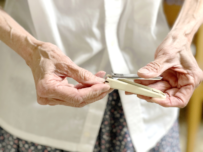 Elderly woman's hand clipping nails with nail clippers