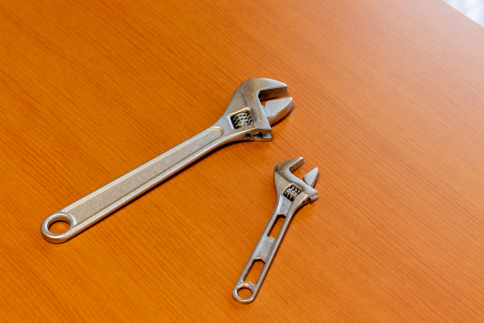Two monkey wrenches on a wooden desk