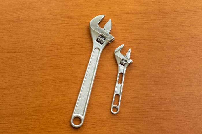 Two monkey wrenches on a wooden board