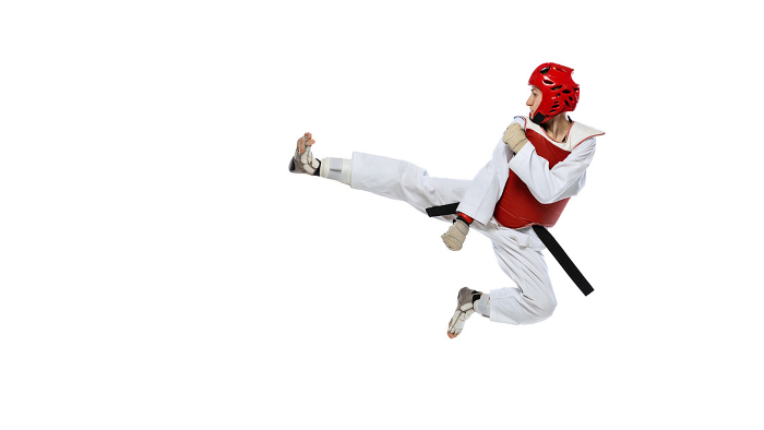 Young girl, taekwondo practitioner training, jumping isolated over white background. Concept of sport, skills Young girl, taekwondo practitioner training, jumping isolated over white background. Concept of sport, education, skills, workout, health. Sportsman wearing white dobok and protective equipment