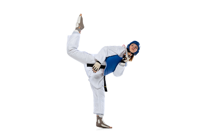 Young girl, taekwondo practitioner strikes forcibly with the foot isolated over white background. Concept of sport, skills Young girl, taekwondo practitioner strikes forcibly with the foot isolated over white background. Concept of sport, education, skills, workout, health. Sportsman wearing white dobok