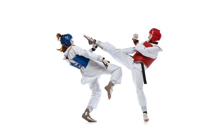 Portrait of two young women, taekwondo athletes practicing, fighting isolated over white background. Concept of sport, skills Sparring. Portrait of two young women, taekwondo athletes practicing, fighting isolated over white background. Concept of sport, education, skills, workout, health. Sportsmen wearing doboks