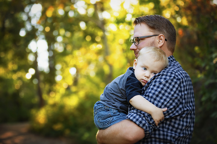 Father holds and comforts his baby boy outdoors in a park in autumn; Edmonton, Alberta, Canada, by LJM Photo / Design Pics
