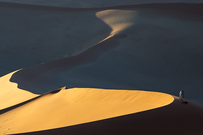 Namibia Sousas Fry Photographer works atop a ridge of a sand dune in Namib Naukluft Park  Sossusvlei, Namibia, by Michael Melford   Design Pics
