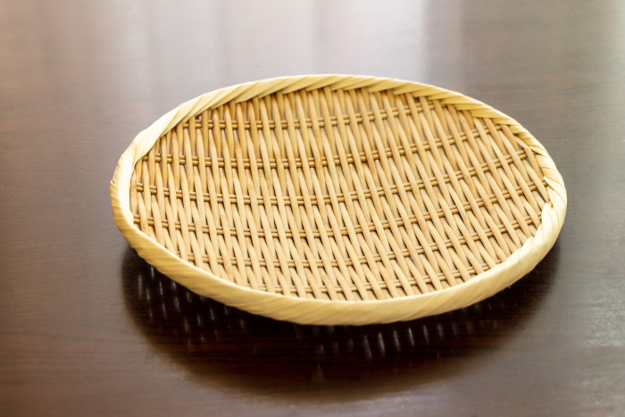 Round bamboo colander placed on a wooden table