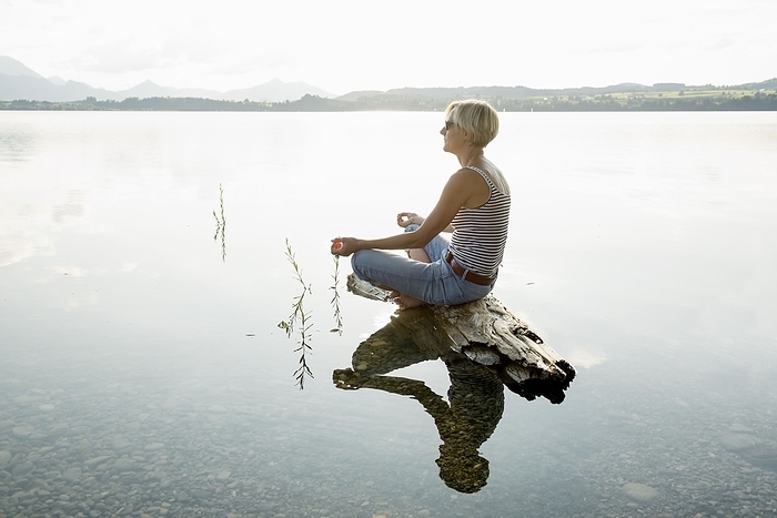 Woman sitting relaxed on a stone, Forggensee, near Füssen, Ostallgäu, Allgäu, Swabia, Upper Bavaria, Bavaria, Germany, Europe, by Daniel Schoenen