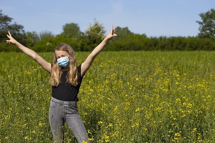 Girl (11) with mouth-nose protection, standing in a rape field, Kiel, Schleswig-Holstein, Germany, Europe, by alimdi / Jana Fernow