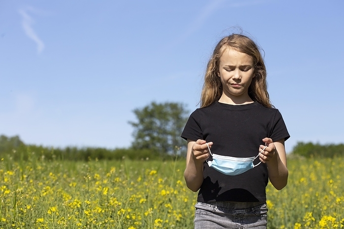 Girl (11) with mouth-nose protection, standing in a rape field, Kiel, Schleswig-Holstein, Germany, Europe, by alimdi / Jana Fernow
