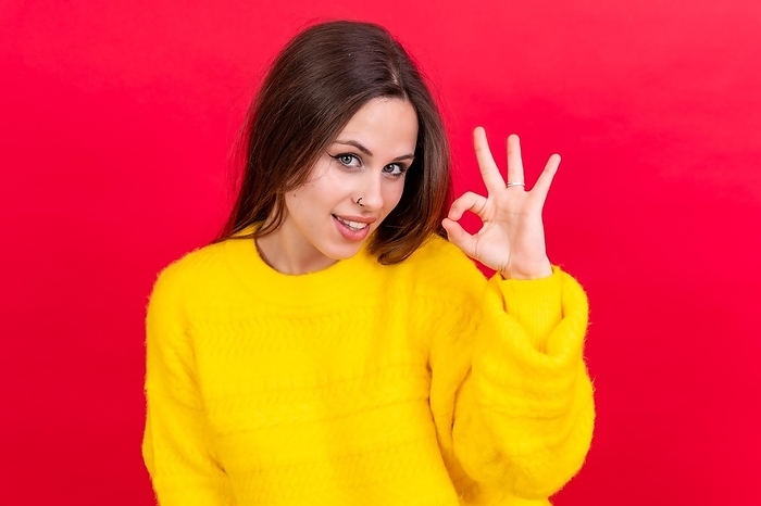 Beautiful woman in casual clothes making ok sign with her hand. successful expression, red background, by Unai Huizi